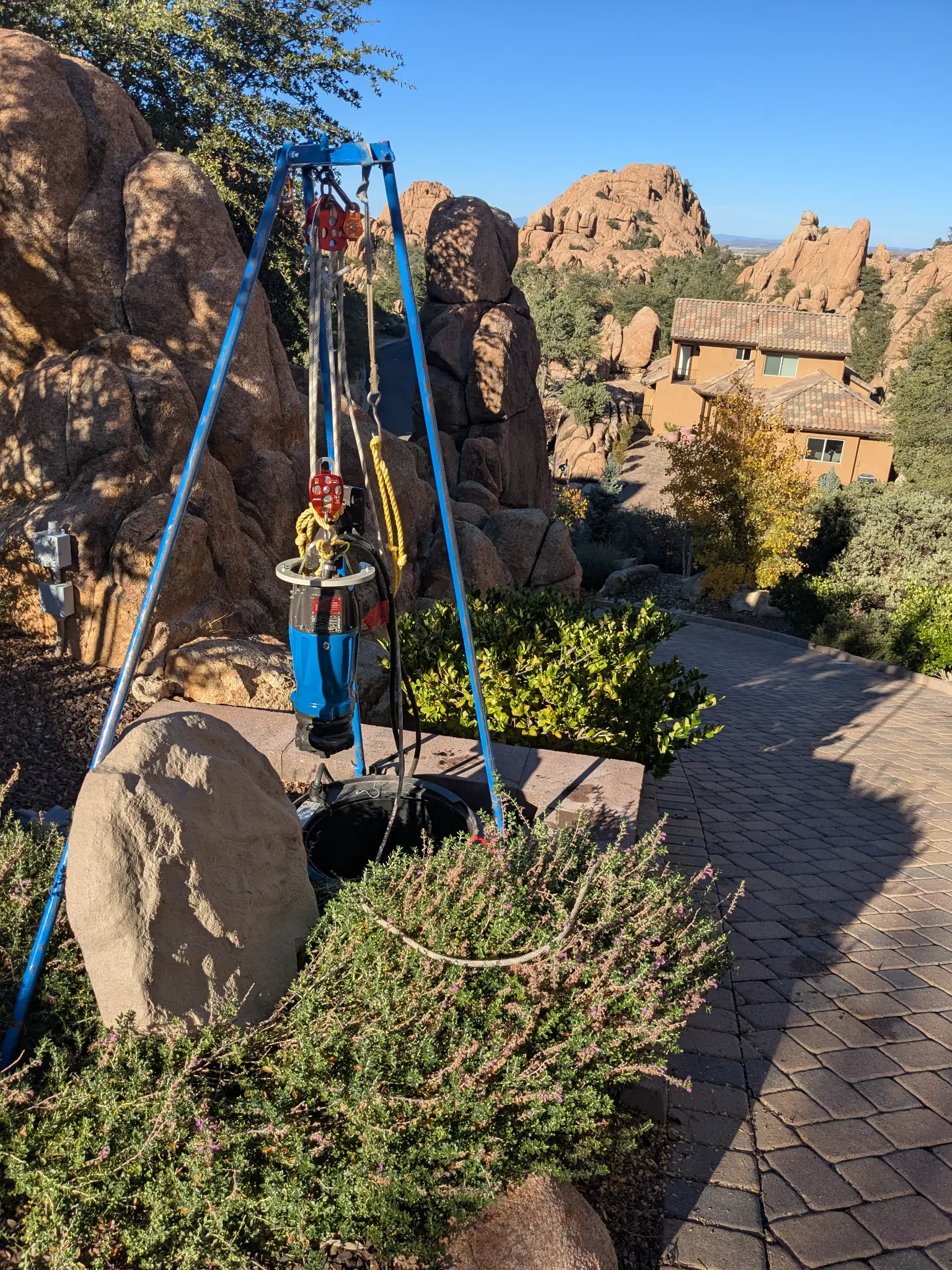 Authentic client field photo of a grinder pump being lifted from a residential pump tank